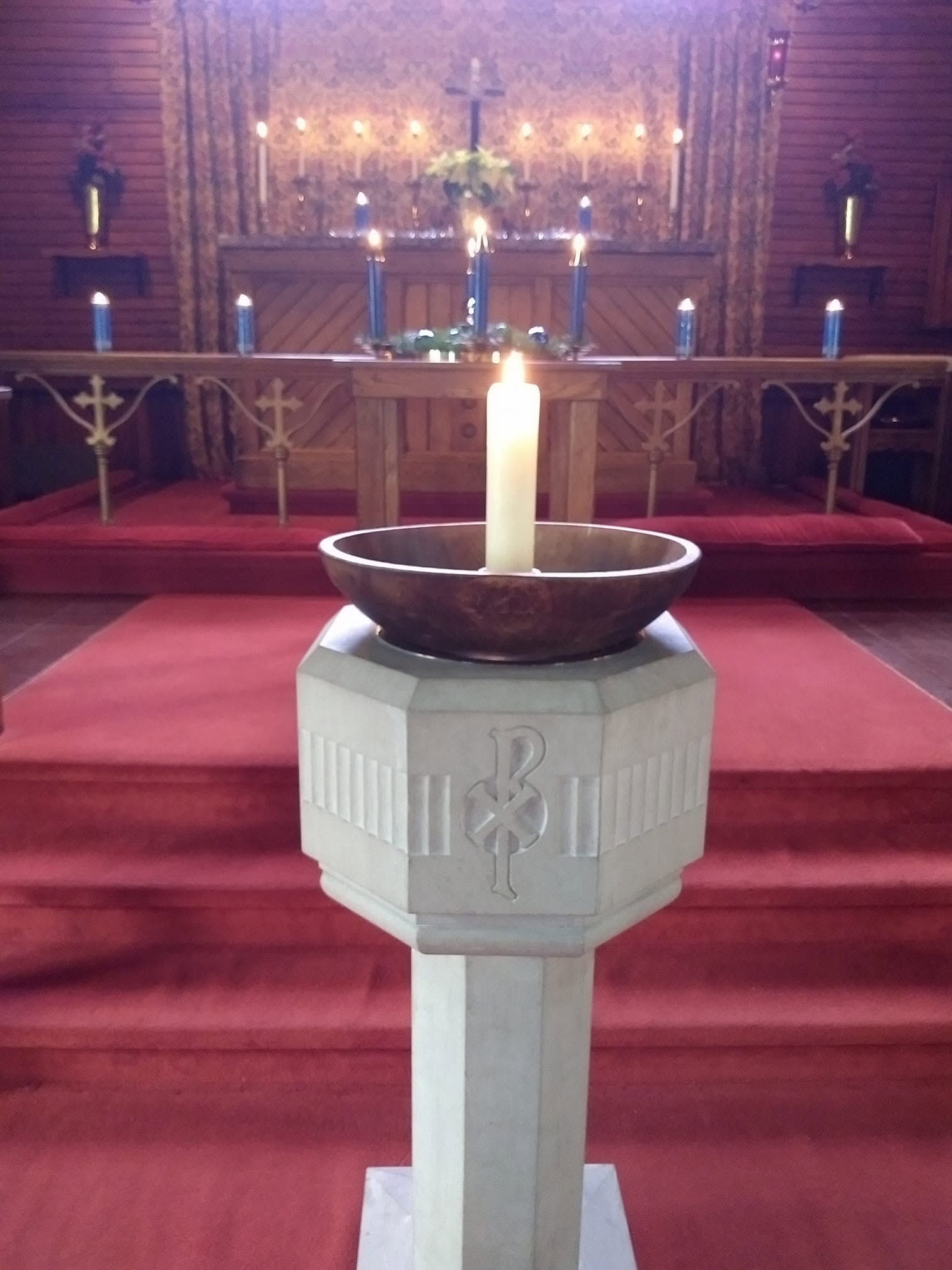 Candles surrounding the altar and baptismal font inside St. John's