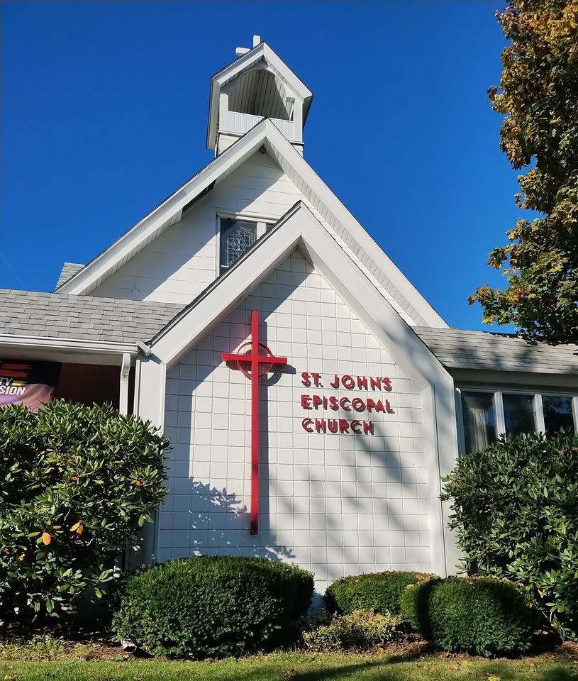 White St. John's Episcopal Church with a red cross and sign in summer
