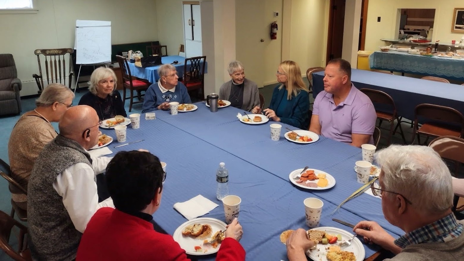 Parishioners sharing coffee and a meal together around a table at a St. John's coffee hour